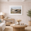 Forgotten Journeys fine art photograph showing a weathered wooden boat resting along the shoreline near Puerto Natales, Patagonia, Chile, presented in a white gallery frame with archival matting in a warm coastal interior setting.